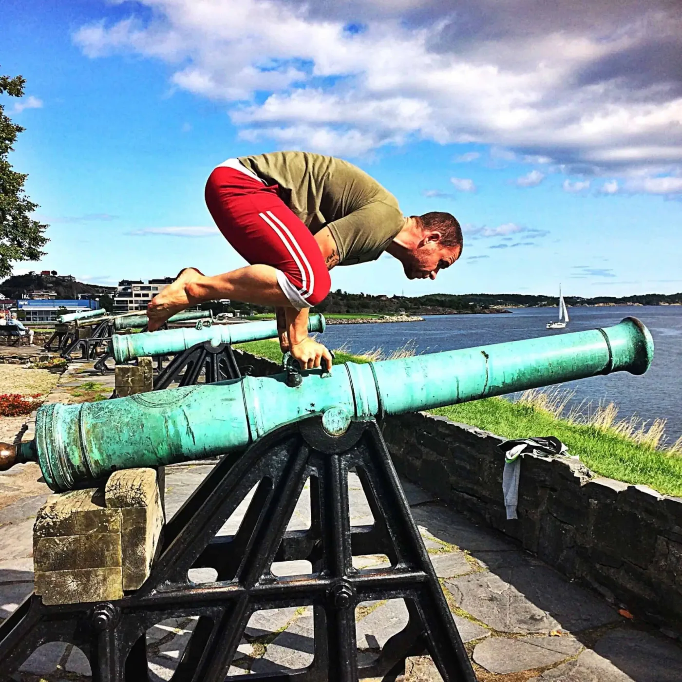 Kenneth balanserer i crow pose på en gammel kanon ved sjøen i Kristiansand